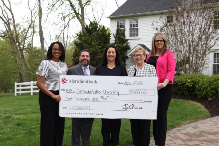 Five people hold an oversized ceremonial check at a contribution presentation